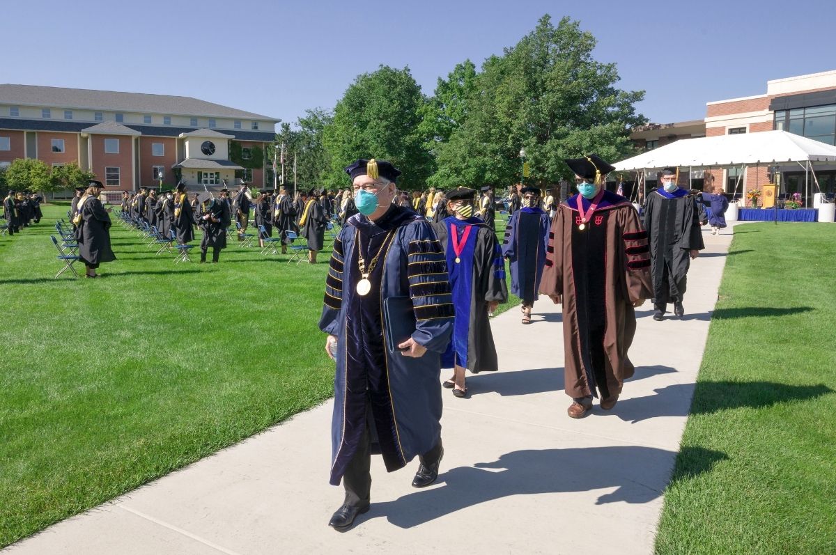 people wearing commencement attire and masks