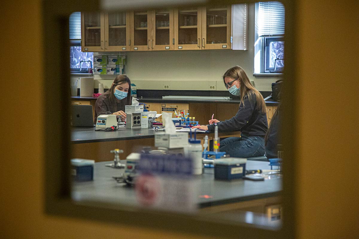 masked students work on equipment in science lab