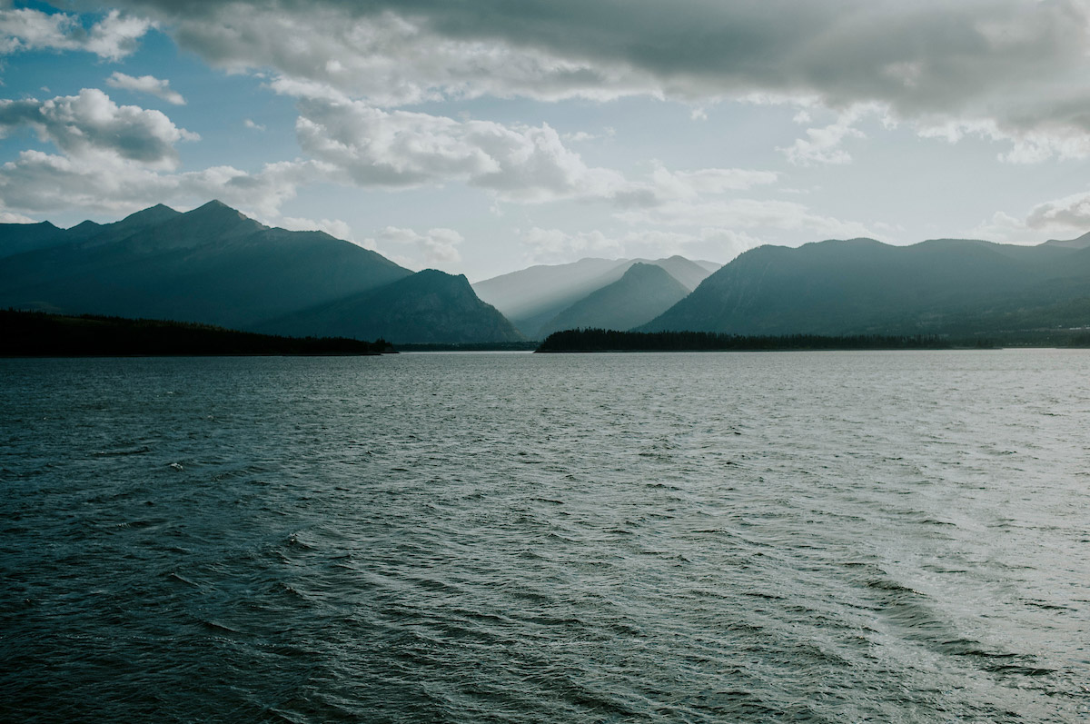 landscape of a cloudy sky with blue mountains and rippled lake