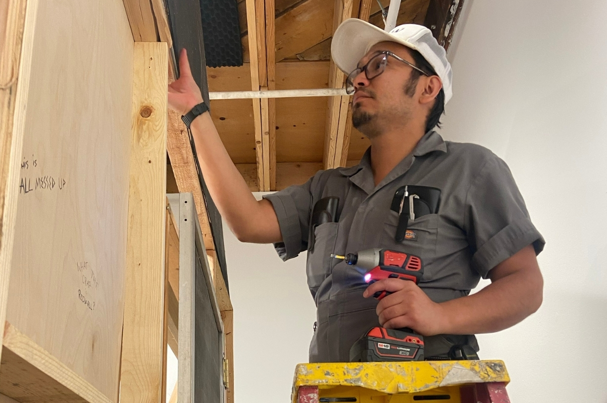 Cipriano on a ladder during the exhibition instllation process