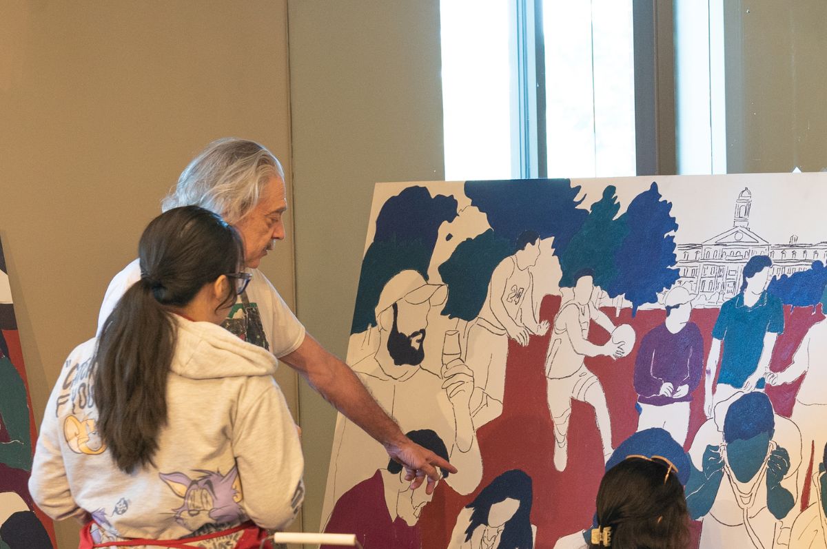 Tony Ortega assists a student with painting his mural