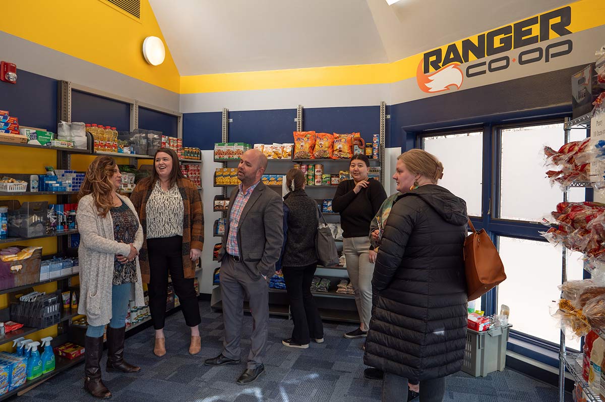 Regis University staff and guests gather at the ribbon cutting ceremony for the new Ranger Co-Op. The shelves are stocked with numerous food and personal hygiene products.