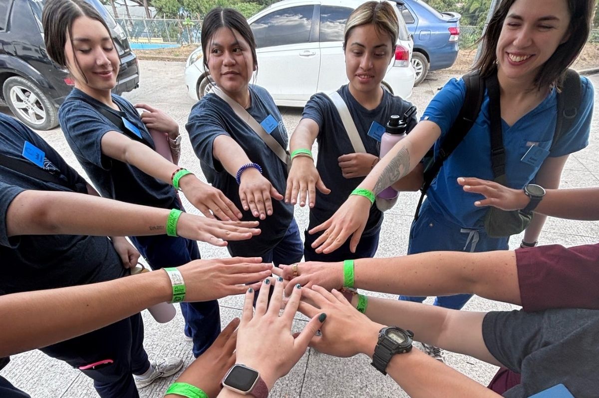 Regis students with their hand together in a circle