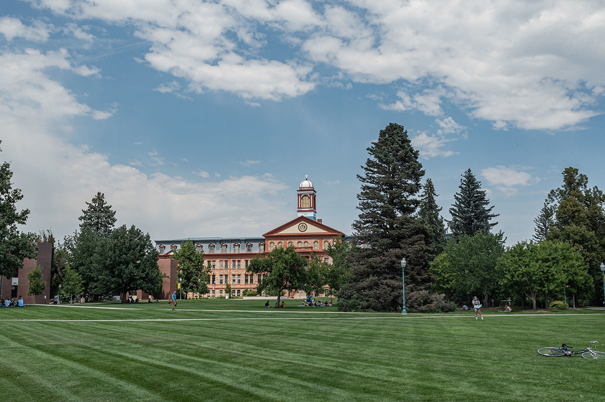 Main Hall stands in the distance, while masked students sit outdoors for class