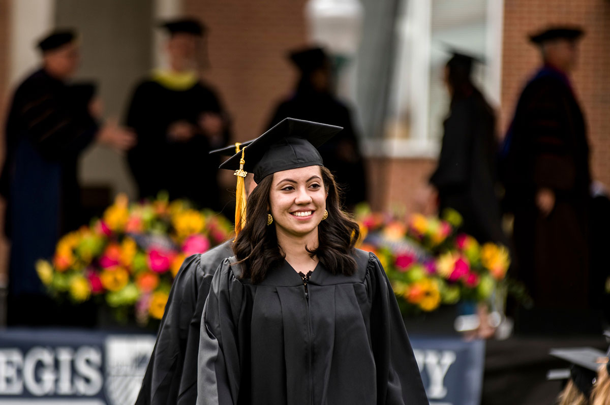 student walks down the aisle with her diploma at the commencement ceremony on campus