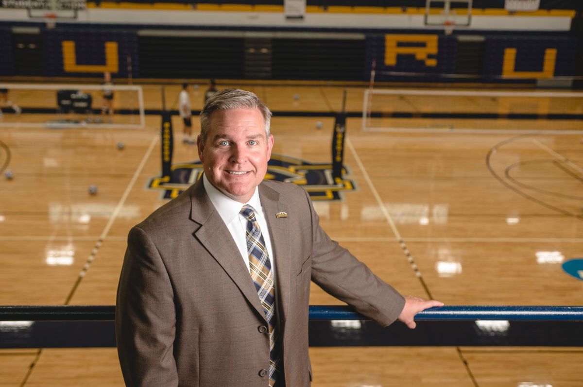 man smiling in front of basketball court