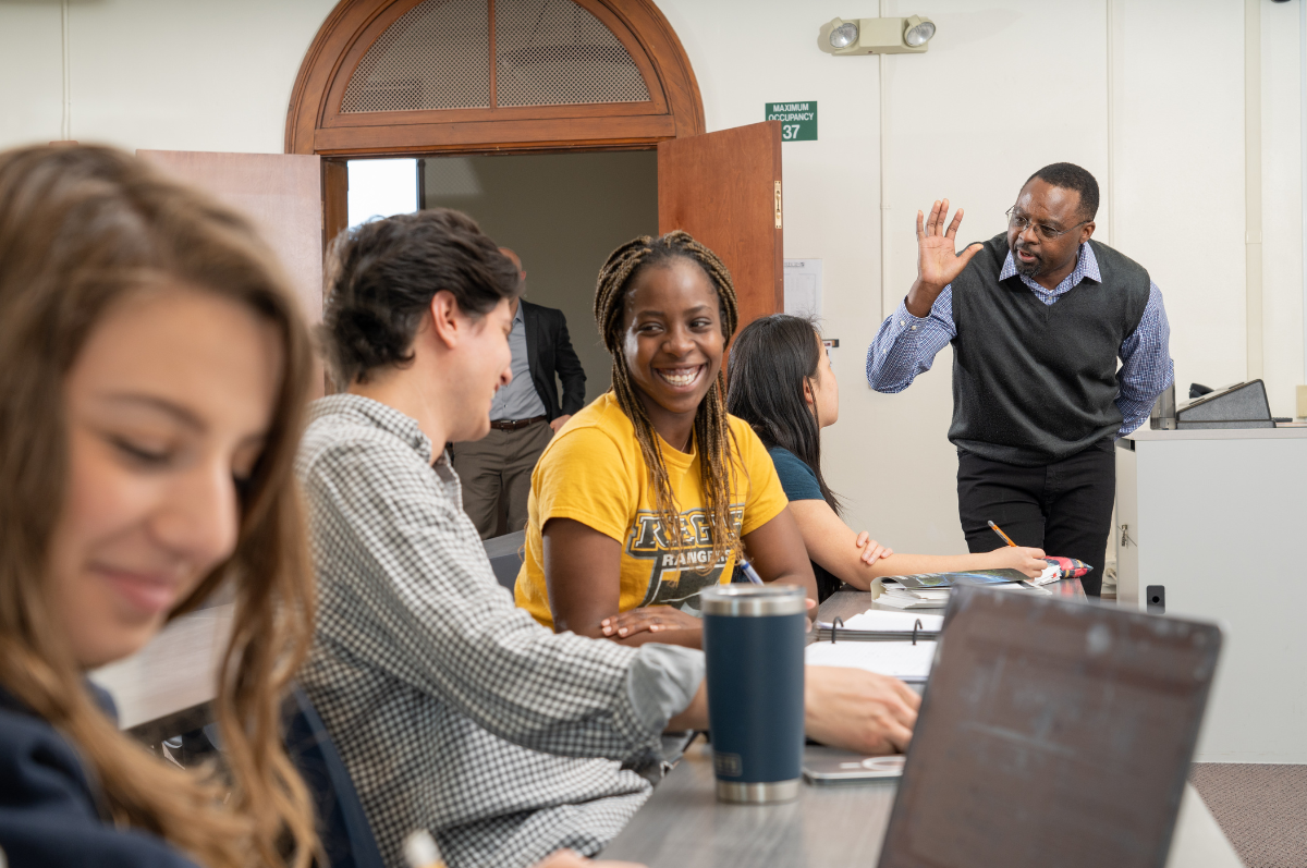 students and and a professor talk in a classroom