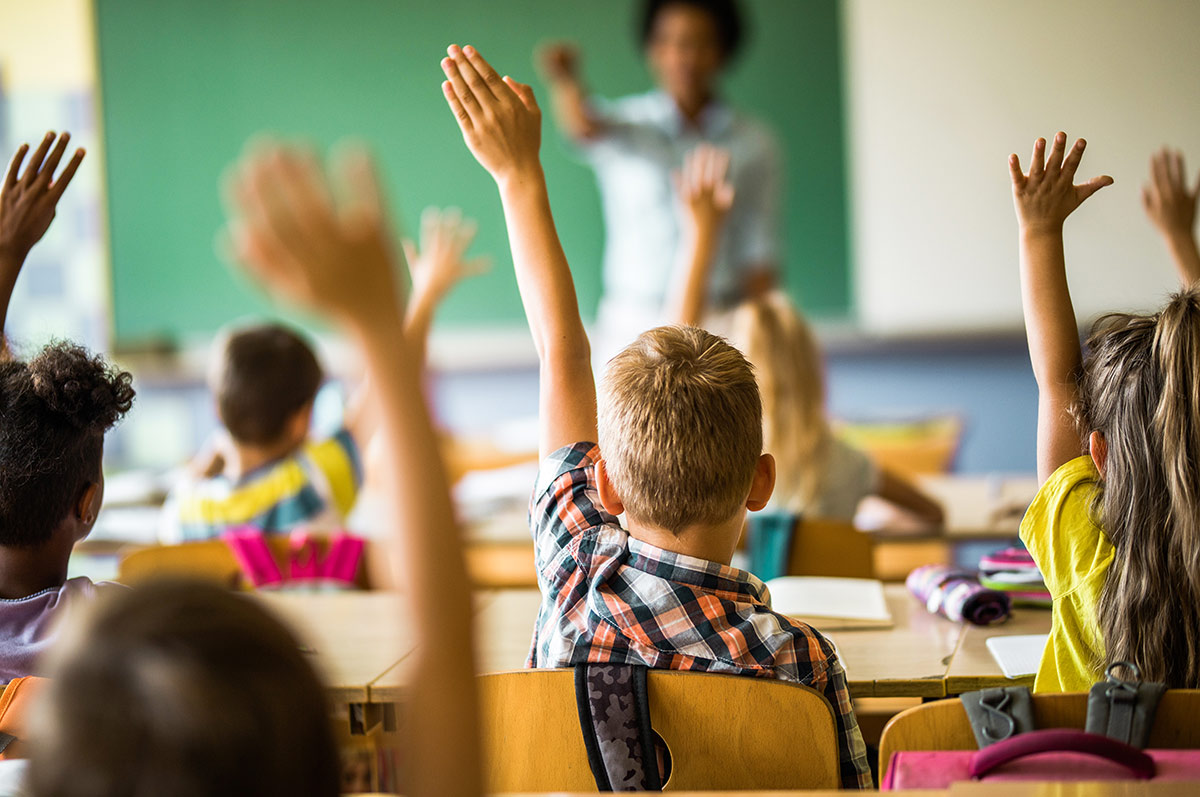 Students in classroom with hands raised