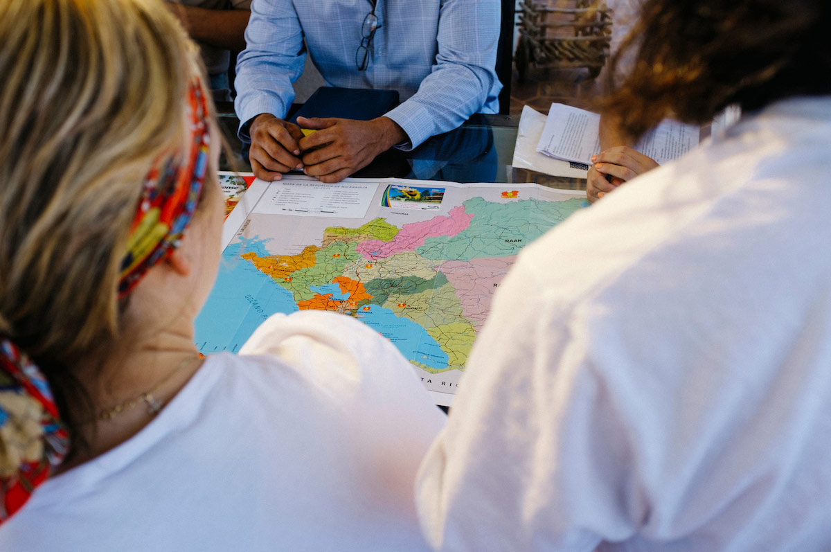 Students bend to examine a map in a classroon