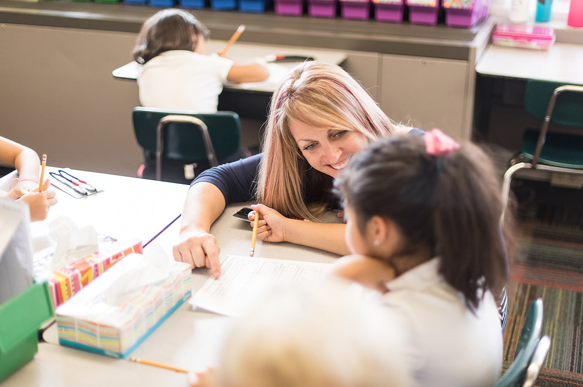 Teacher helping elementary aged student in classroom