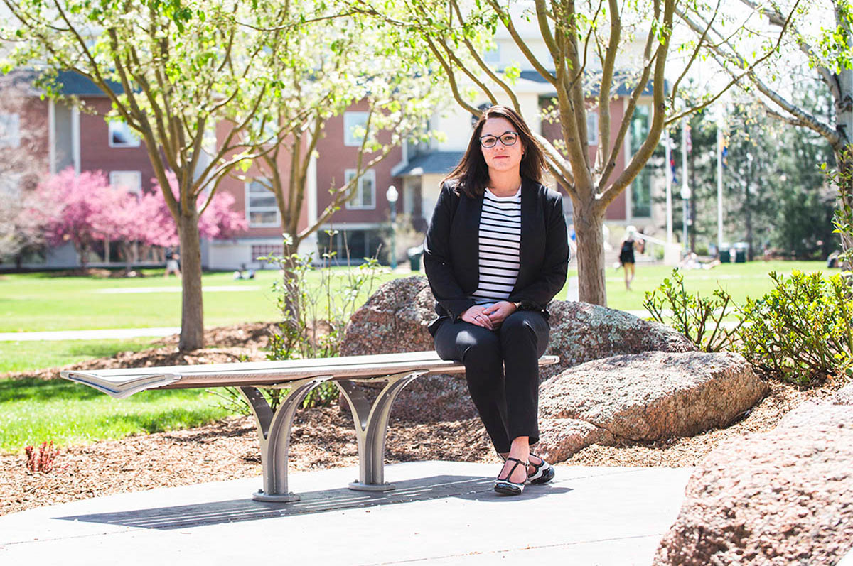 Regis graduate Brandie Bernstein sits on a bench at Regis' Northwest Denver Campus