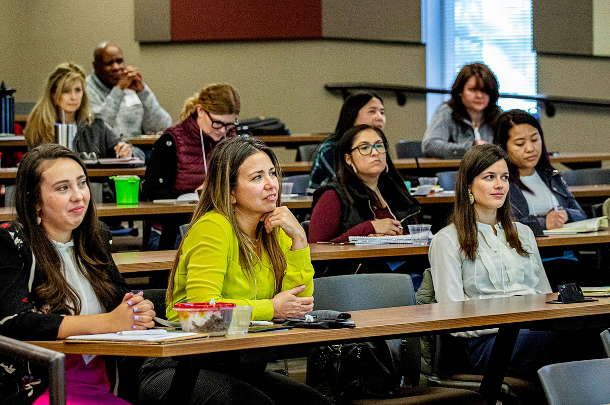 women sit at table as they listen to speaker